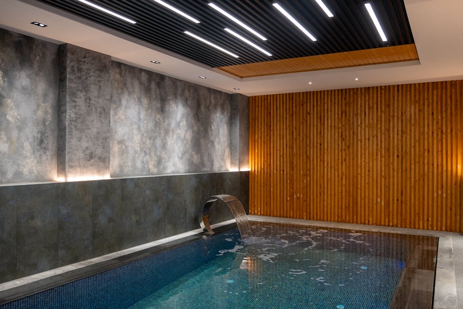 Relaxing indoor pool area featuring modern lighting and elegant wood paneling design.